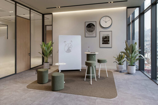 neudoerfler Create Box in hellen Grüntönen mit Stehtisch, Sitzmöbeln, Teppich und Whiteboard für kreativen Austausch im Büro.