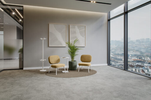 Officebox by neudoerfler: a lounge set in light, cozy colors consisting of two lounge chairs, a side table, a plant stand, and a coat rack.